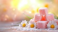Pink sugar cubes stacked with fresh daisy flowers on rustic wooden surface against soft bokeh background, creating sweet romantic food composition.