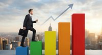 Professional businessman in dark suit climbing colorful bar chart steps with upward arrow against city skyline backdrop representing career growth and success.