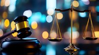 Wooden gavel and golden scales of justice on dark surface with blurred city lights bokeh background for legal services and law firm concepts.