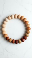 Natural wooden beads arranged in circle on marble surface showcasing earth tone gradient from light to dark brown for jewelry making and craft projects.