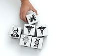Hand arranging white cubes with medical and science symbols including DNA, lightbulb, caduceus for healthcare innovation concepts on white background.