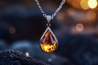 Elegant teardrop amber pendant necklace with silver chain against blurred bokeh background, luxury jewelry photography with warm glowing gemstone.