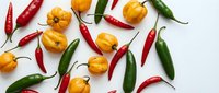 Colorful hot chili peppers scattered on white background. Fresh red and green spicy peppers with yellow habaneros for cooking and seasoning culinary ingredients.