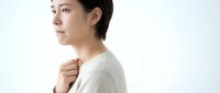 Young Asian woman in beige sweater looking thoughtfully to side against clean white background for lifestyle and wellness content.