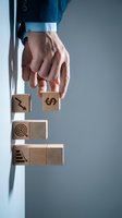 Businessman hand placing wooden cube with dollar symbol on stack representing financial growth and investment strategy for business success.