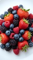 Fresh mixed berries collection with strawberries, blueberries, raspberries and blackberries on white background for healthy eating and nutrition concepts.