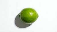 Fresh green lime isolated on white background with natural shadow, ready for food and beverage design projects.