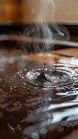 Water droplet splashing into dark liquid with steam rising, creating dynamic ripples and waves. Macro shot suitable for beverage, coffee, or abstract liquid motion projects.