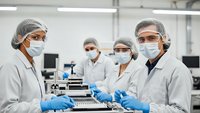 Team of diverse laboratory technicians in protective gear working with scientific equipment in modern sterile research facility for quality control testing.