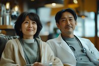 Middle-aged Asian couple enjoying coffee at cafe. Woman in sweater and man in white jacket share warm smiles during casual date. Intimate lifestyle portrait with soft lighting.