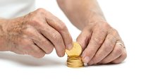 Senior male hands stacking golden coins, representing savings, investment, wealth accumulation, and financial planning for retirement or future security.