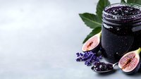 Dark purple berry jam in glass jar with fresh figs, lavender flowers and green leaves on light gray background. Food styling composition with copy space.