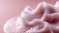Soft pink foam bubbles in macro photography showing delicate texture and patterns of soap or cosmetic product against rosy background. Suitable for beauty and spa marketing.