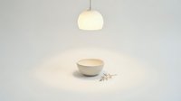 Minimalist white ceramic bowl on clean surface under warm pendant light creating soft shadows and peaceful dining atmosphere for modern kitchen design.
