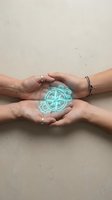 Multiple hands holding glowing compass rose symbol against neutral background, representing unity, direction, and shared vision for teamwork and collaboration concepts.