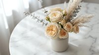 Elegant neutral floral arrangement with cream roses and pampas grass in ceramic vase on marble table for home decor and interior design styling.
