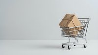 Miniature shopping cart filled with cardboard delivery boxes on white background, representing e-commerce, online shopping, and fast shipping services for retail and logistics concepts.