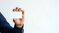 Male hand holding blank white business card against neutral background for corporate branding and professional networking purposes.