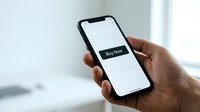 Hand holding smartphone with Buy Now button on screen, mobile shopping and e-commerce concept for digital marketing use.