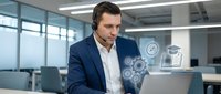 Professional businessman in navy suit using laptop with digital technology icons in modern office workspace for business presentations and corporate communications.