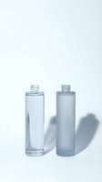 Two empty glass cosmetic bottles on white background with soft shadows for skincare and beauty product packaging design.