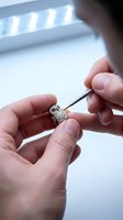 Skilled jeweler carefully crafting intricate owl pendant with precision tools under professional lighting in modern workshop studio.