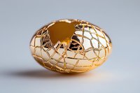 Cracked golden egg shell with intricate network pattern reveals inner void against neutral background, symbolizing fragility and transformation in artistic still life.