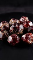 Raw red garnet gemstones collection on dark background showcasing natural mineral crystals for jewelry making and geological study purposes.