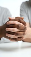 Diverse hands clasped together showing unity and cooperation between different ethnicities in professional business or teamwork setting.