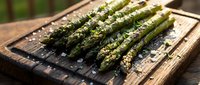 Fresh asparagus spears with seasoning on wooden cutting board, ready for cooking or grilling. Suitable for food blogs, recipes, and culinary content.