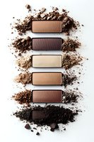Crushed makeup eyeshadow palette in neutral earth tones with brown and beige rectangular color samples arranged vertically on white background with powder texture.