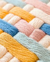 Colorful woven cotton threads in pastel yellow, blue, pink and white creating textured pattern macro close up, soft focus background for craft and textile design.