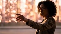 African American businesswoman using smartphone with warm bokeh lights background creating professional evening atmosphere for corporate communication.
