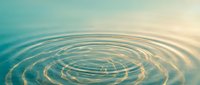Concentric water ripples spreading across calm turquoise surface with soft gradient lighting creating peaceful zen meditation atmosphere for wellness concepts.
