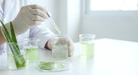 Laboratory scientist in white coat conducting green liquid chemical analysis with test tubes and beakers for research and development experiments.