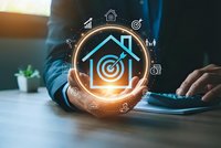 Businessman holding glowing house icon with target symbol and digital marketing icons for real estate investment and property management concepts.