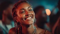 Young African American woman with braided hair smiling joyfully at night event with colorful bokeh lights in background for lifestyle and celebration content.