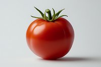 Fresh ripe red tomato with green stem and leaves isolated on white background, casting soft shadow. Clean minimalist food photography for culinary use.