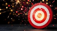 Red and white target bullseye with explosive sparks and golden particles bursting from center on dark background for business success concepts.