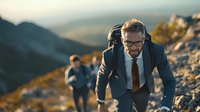 Businessman in formal suit climbing rocky mountain path at sunset, demonstrating leadership and determination in challenging environment.