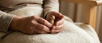 Pregnant woman hands gently resting on belly in cozy home setting. Maternity, motherhood, expecting baby, prenatal care, family planning concept.