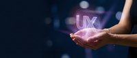 Hands holding glowing UX letters with pink light effects on dark background for user experience design and digital technology concepts.