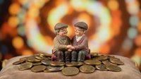 Elderly couple figurines sitting on pile of golden coins with warm bokeh background representing retirement savings and financial security planning.