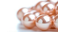 Luxurious rose gold metallic spheres with soft reflective surface against white background, macro photography showing elegant pearl-like texture and shine.