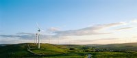 Wind turbines on rolling green hills at sunset, generating renewable energy for sustainable power production and clean electricity generation.