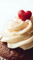 Chocolate cupcake with vanilla buttercream frosting topped with red heart-shaped candy and pink sprinkles for Valentine's Day celebration and romantic desserts.