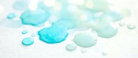 Turquoise and teal watercolor paint drops and splatters on white textured paper creating organic fluid shapes for artistic projects and creative designs.