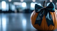 Orange pumpkin with elegant black satin bow on blurred background, festive autumn decoration for Halloween or Thanksgiving.