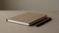 Minimalist kraft paper notebook with blank pages and wooden pencils on neutral background for creative writing and sketching projects.