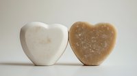 Two heart-shaped handmade soap bars in white and brown colors with natural texture for spa wellness skincare routine and romantic bath products.